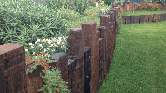 Sleeper retaining wall holding back a native garden bed in a Perth backyard